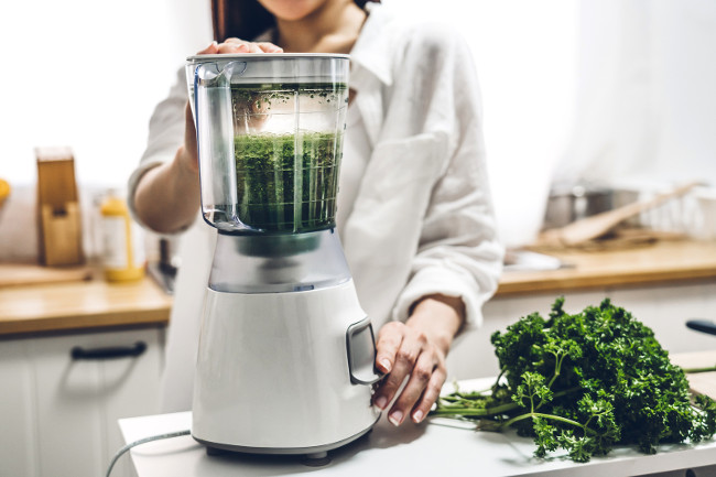 Healthy woman enjoy making green vegetables detox cleanse and green fruit smoothie with blender in kitchen at home.dieting concept.healthy lifestyle