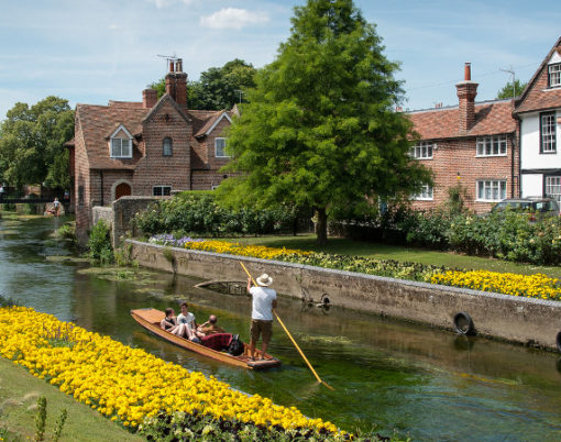 Canterbury Kent United Kingdom - 7 July 2017:Tourist people taking a romantic boat ride in the canal of the river stour at the beautiful Chartham gardens in the center of the city of Canterbury in Kent United Kingdom.