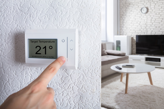 Close-up Of A Person's Hand Adjusting Digital Thermostat At Home