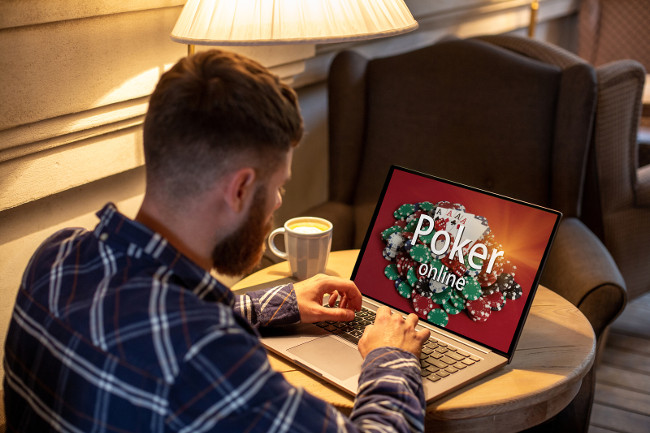 Game online concept. Close-up top view of a man playing poker on laptop. Young man playing via netbook during work-break in coffee shop, male sitting in front open laptop computer. Advertising content