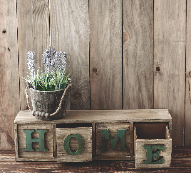 Storage box with Home letters and flowers in a pot on wooden background, home rustic decor, cottage living