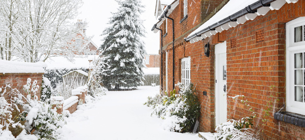 English country home in winter with a driveway covered in snow