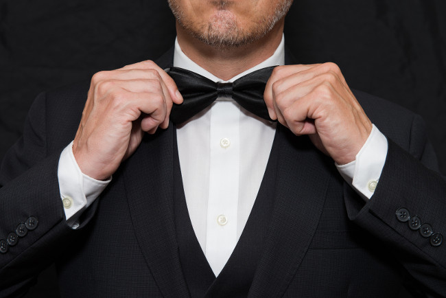 Close-up of a gentleman wearing Black Tie straightens his bowtie.