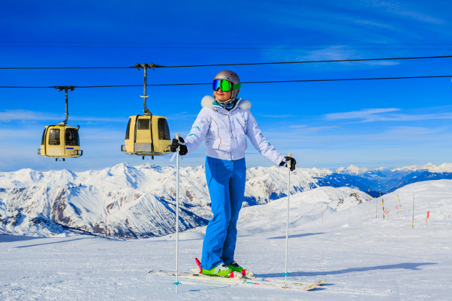 Girl on skiing on snow on a sunny day in the mountains. Ski in winter seasonon, the tops of snowy mountains in sunny day. Meribel resort, 3 vallees, France.