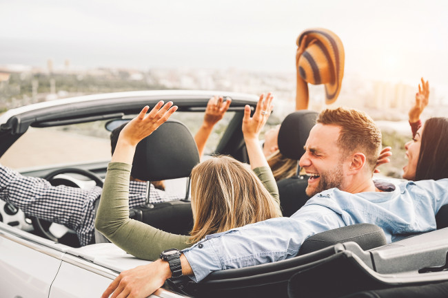 Group of friends having fun in convertible car during road trip at sunset - Young travel people driving a cabriolet during summer holidays - Happiness, vacation and youth lifestyle concept