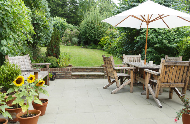 London garden in summer with patio, wooden garden furniture and a parasol or sun umbrella