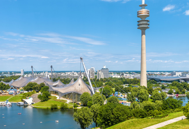 Munich Olympiapark in summer, Germany. It is the Olympic Park, landmark of Munich. Scenic view of former sport area from above. Cityscape of Munich with communication tower. Skyline of Munich city.