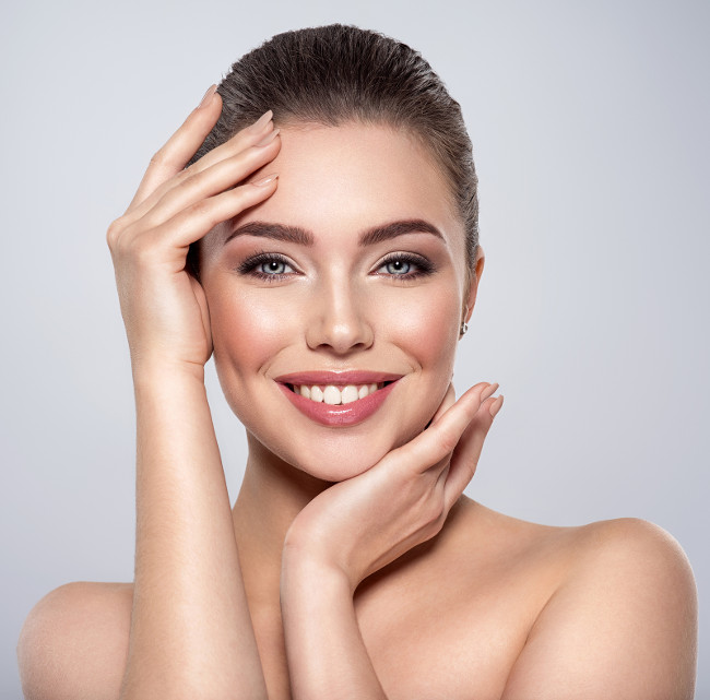 Beauty face of the young beautiful smiling woman  with a fresh healthy skin. Closeup portrait of an attractive caucasian female. Skin care concept. Woman with a smokey eye makeup. Beauty treatment.