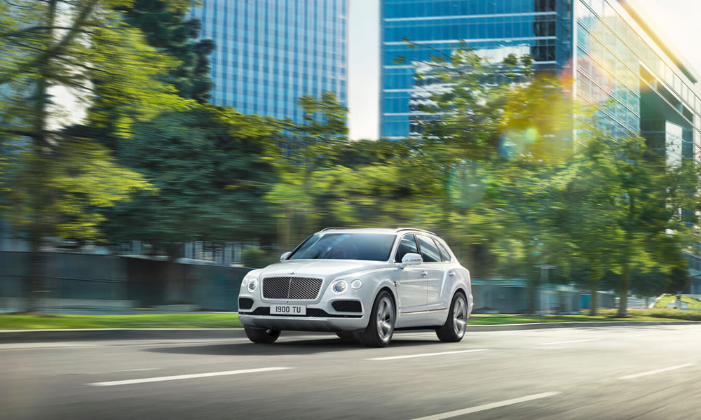 Bentayga Hybrid driving on city road with buildings and trees in background 1920x805