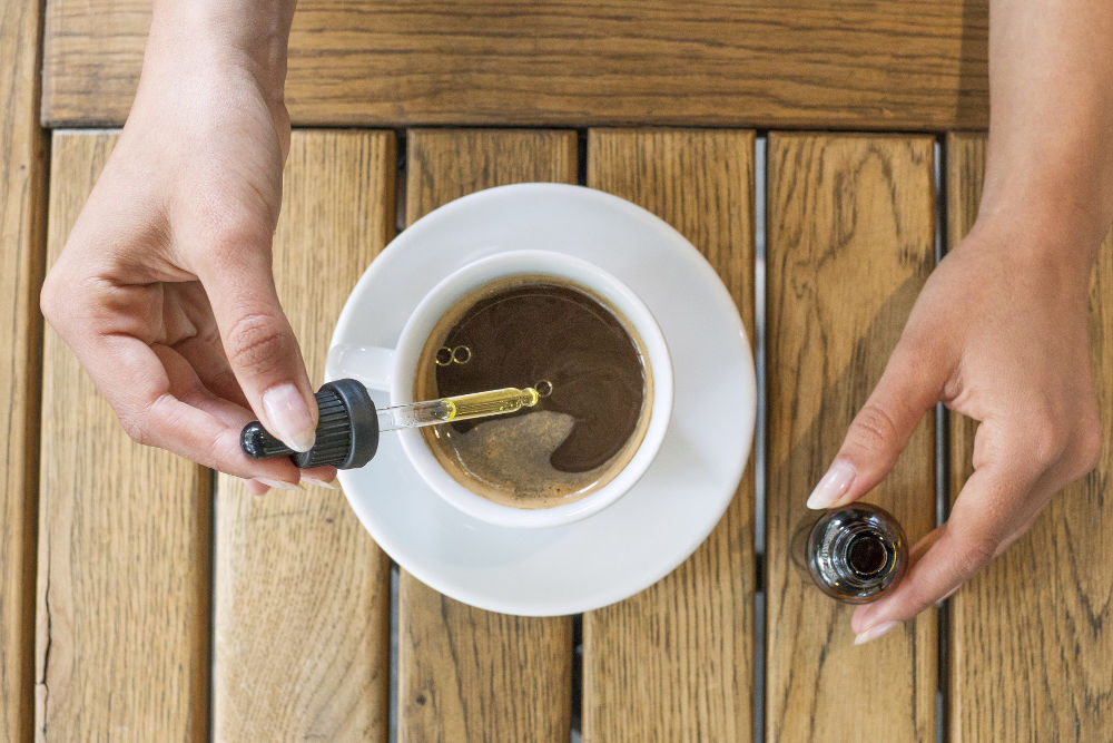 CBD oil being added to a cup of coffee