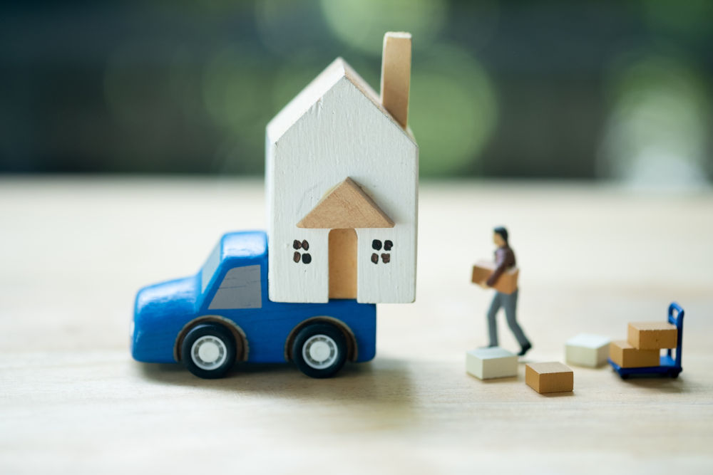 Miniature worker moving thing to miniature house on blue car