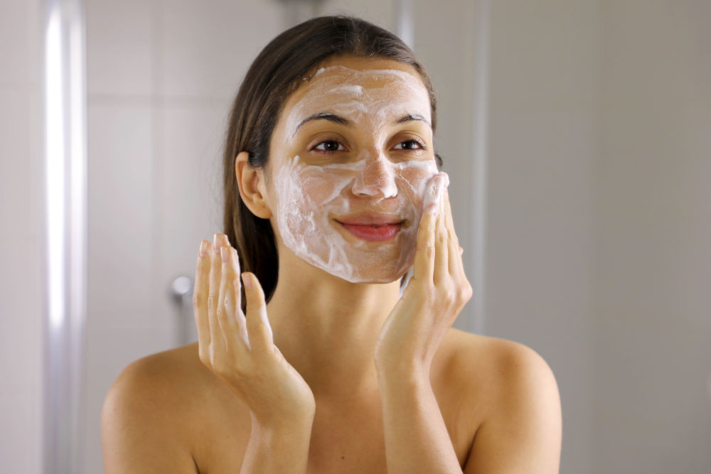 Woman washing face with foaming soap