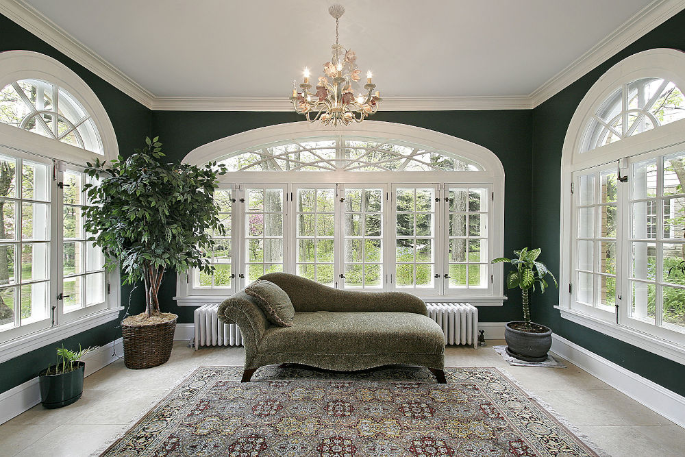 Sunroom in luxury home with sofa and wall of windows