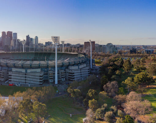 Aerial shot of the Melbourne Cricket Ground with Melbourne city skyline and late afternoon sun behind