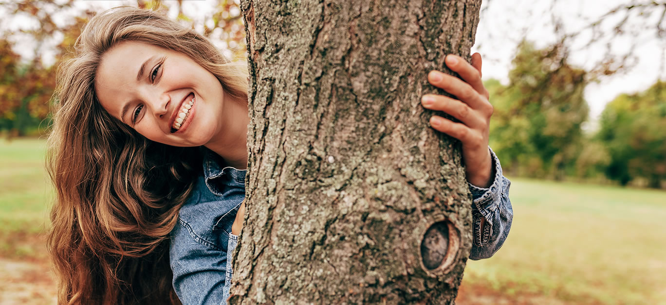 happy woman behind a tree