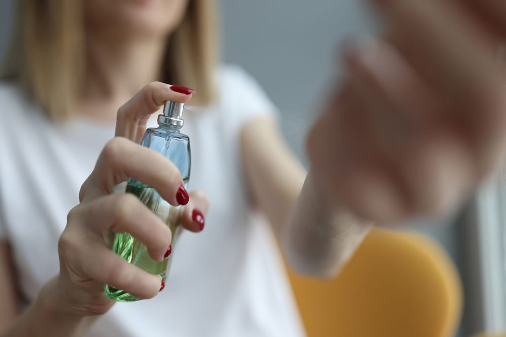 Woman applying feminine eau de parfum on her wrist closeup
