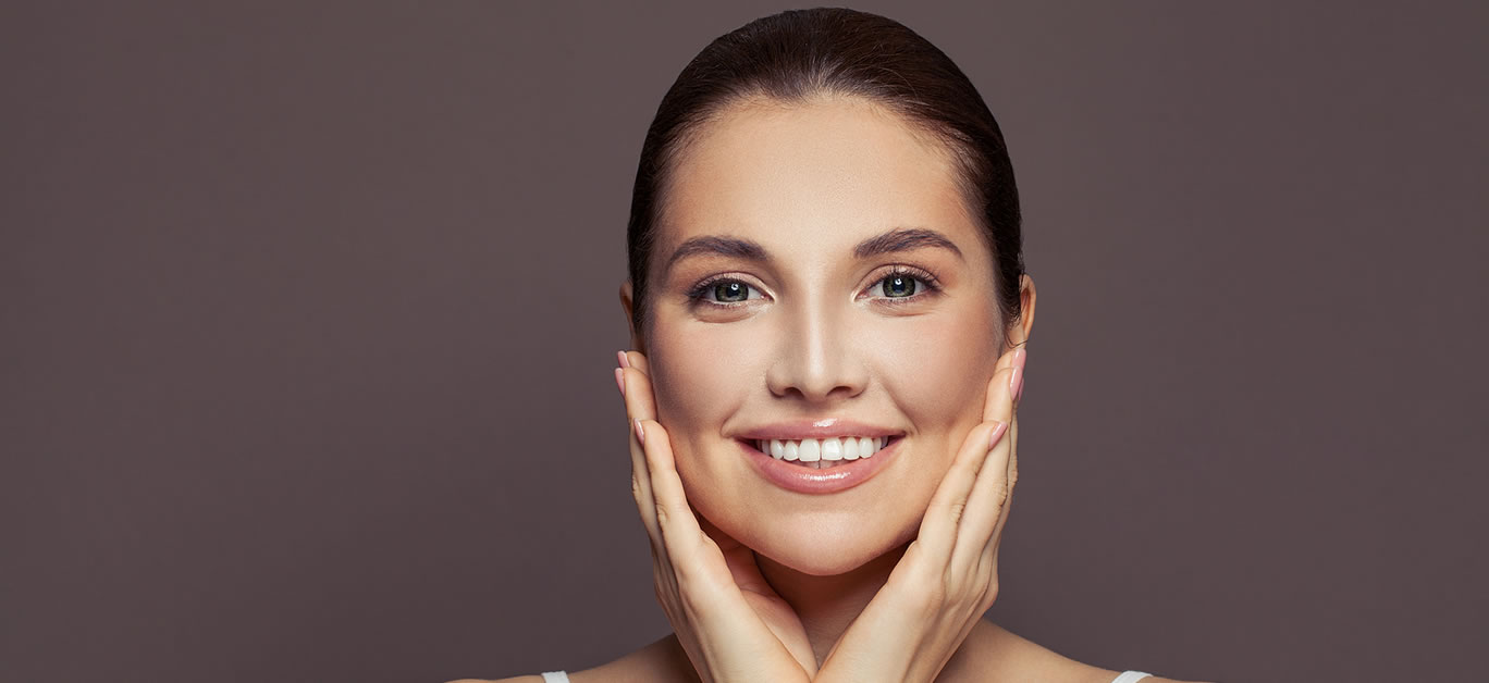 Happy young woman spa model with clear skin smiling on brown background. Skincare and facial treatment concept