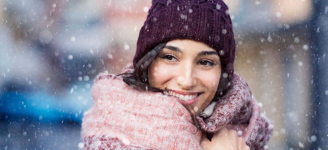 Smiling woman wearing wool bonnet and scarf in a winter cold day