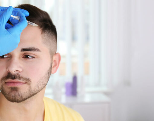 Young man with hair loss problem receiving injection in salon