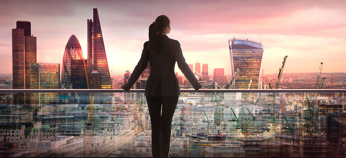 Young woman looking over the City of London business and banking aria with skyscrapers at sunset.