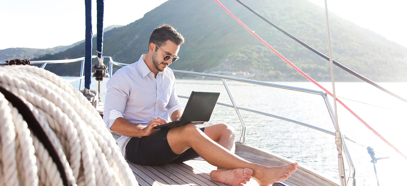 Man working on yacht office with laptop