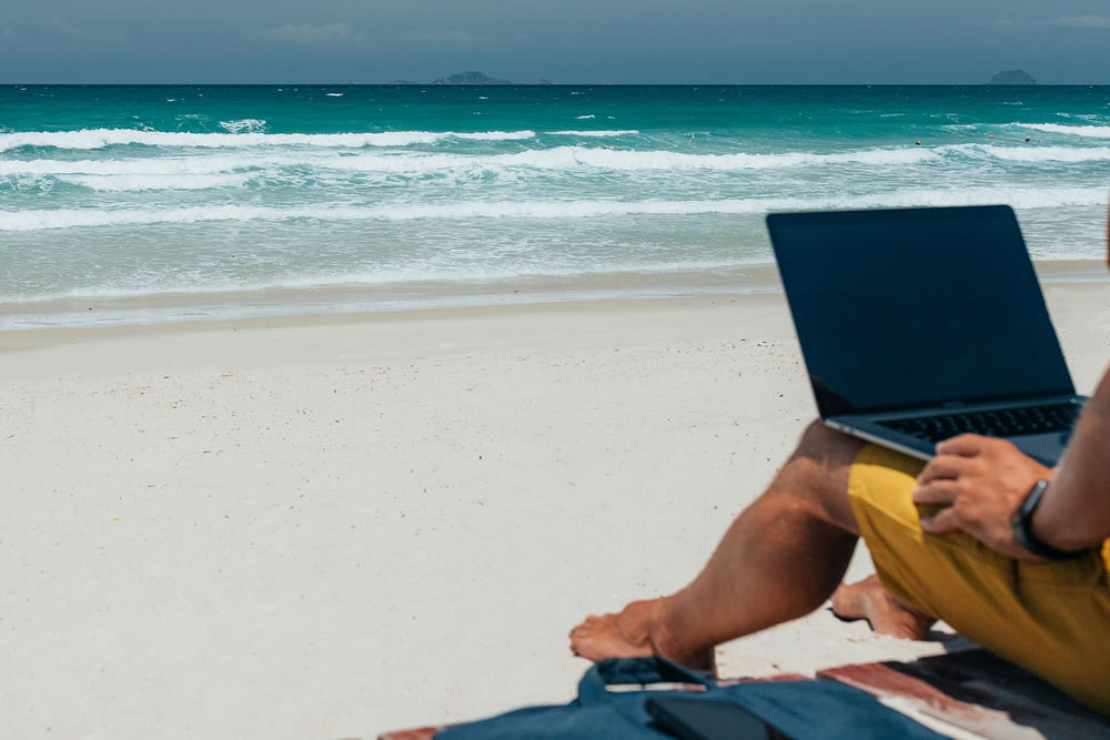 Man on laptop on beach