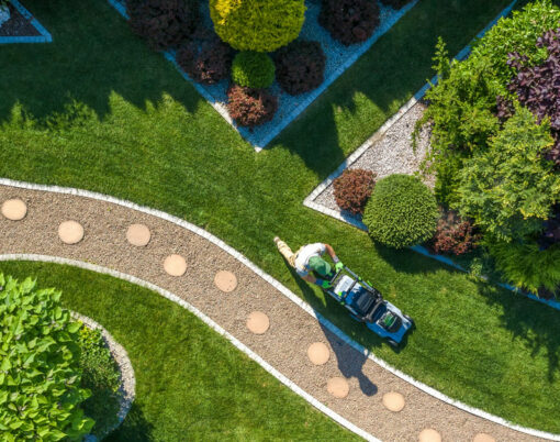 Gardener with Grass Mower Trimming Beautiful Backyard Garden Lawn