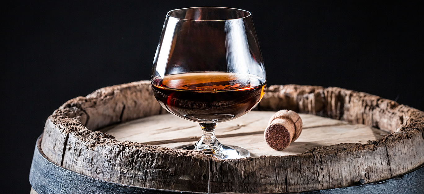 Glass of good whisky on oak barrel