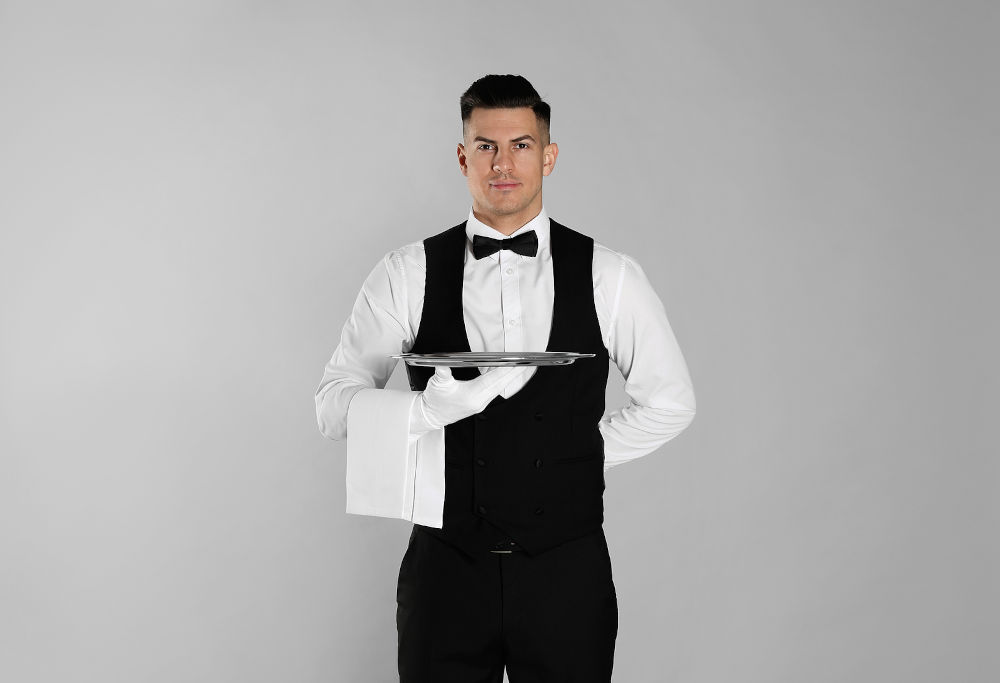 Handsome butler with tray on light grey background