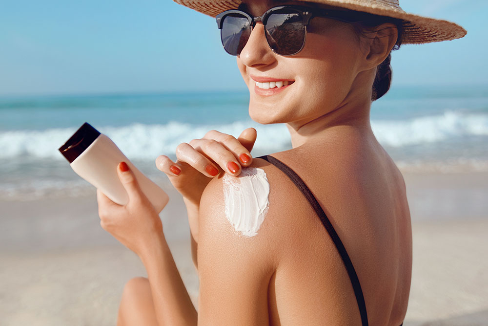 Women wearing hat, sunglasses and applying sunscreen 