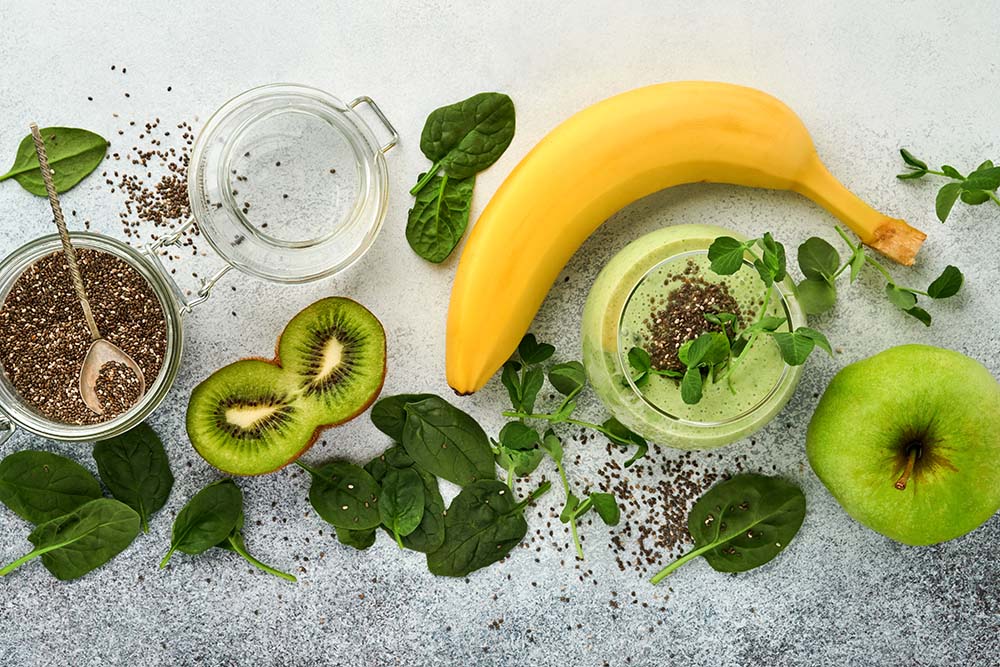 Green smoothie made with banana, chia seeds, kiwi, apple, spinach and micro peas