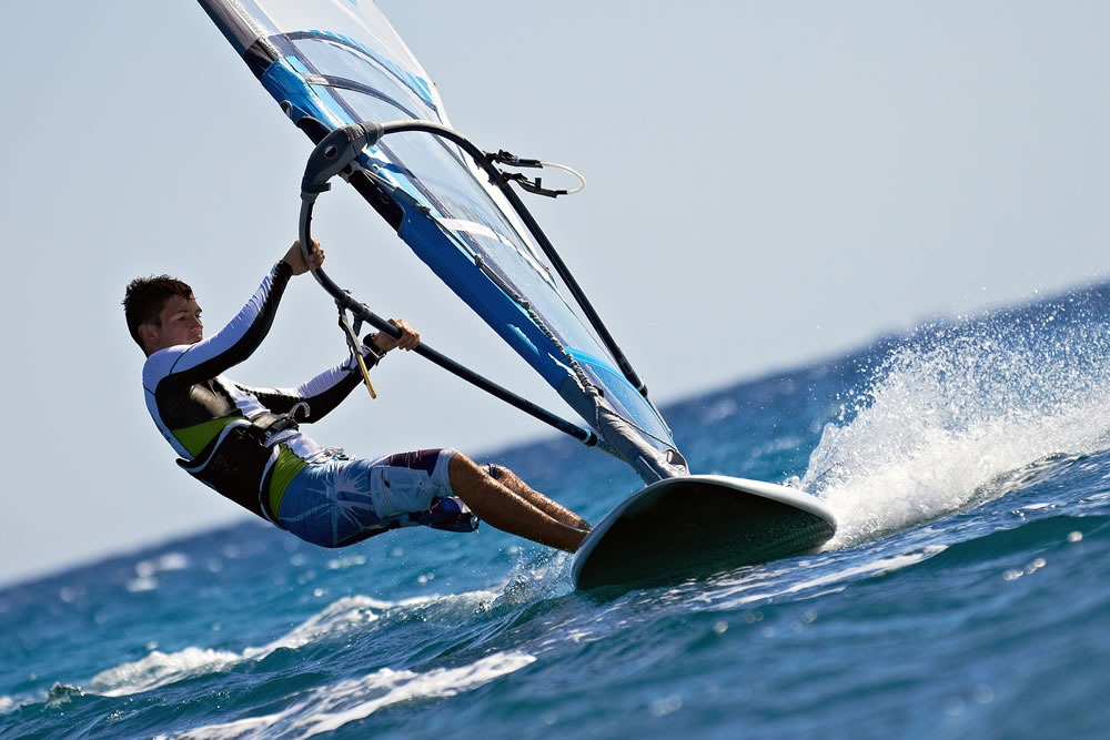 Side view of young windsurfer close-up mooving speedly