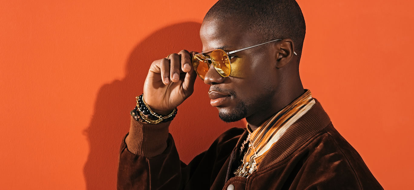 side view of handsome stylish african american man adjusting sunglasses on red