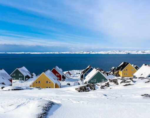 Yellow blue red and green inuit houses covered in snow at the fjord of Nuuk city Greenland