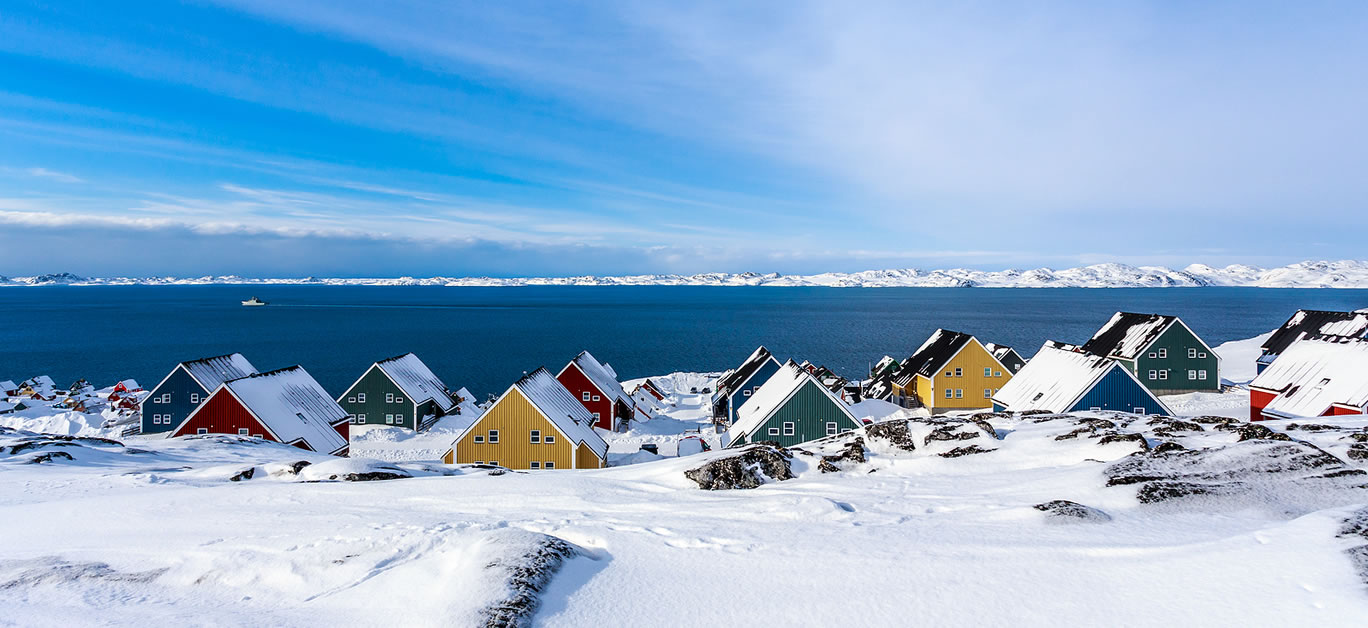 Yellow blue red and green inuit houses covered in snow at the fjord of Nuuk city Greenland