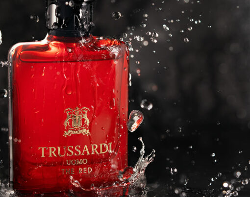 Perfume Trussardi bottle against stone wall under splashes of water on dark stone background