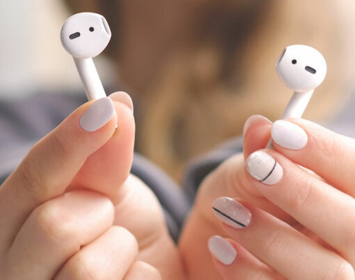 White wireless airpods in female hands. Modern mobile technology.