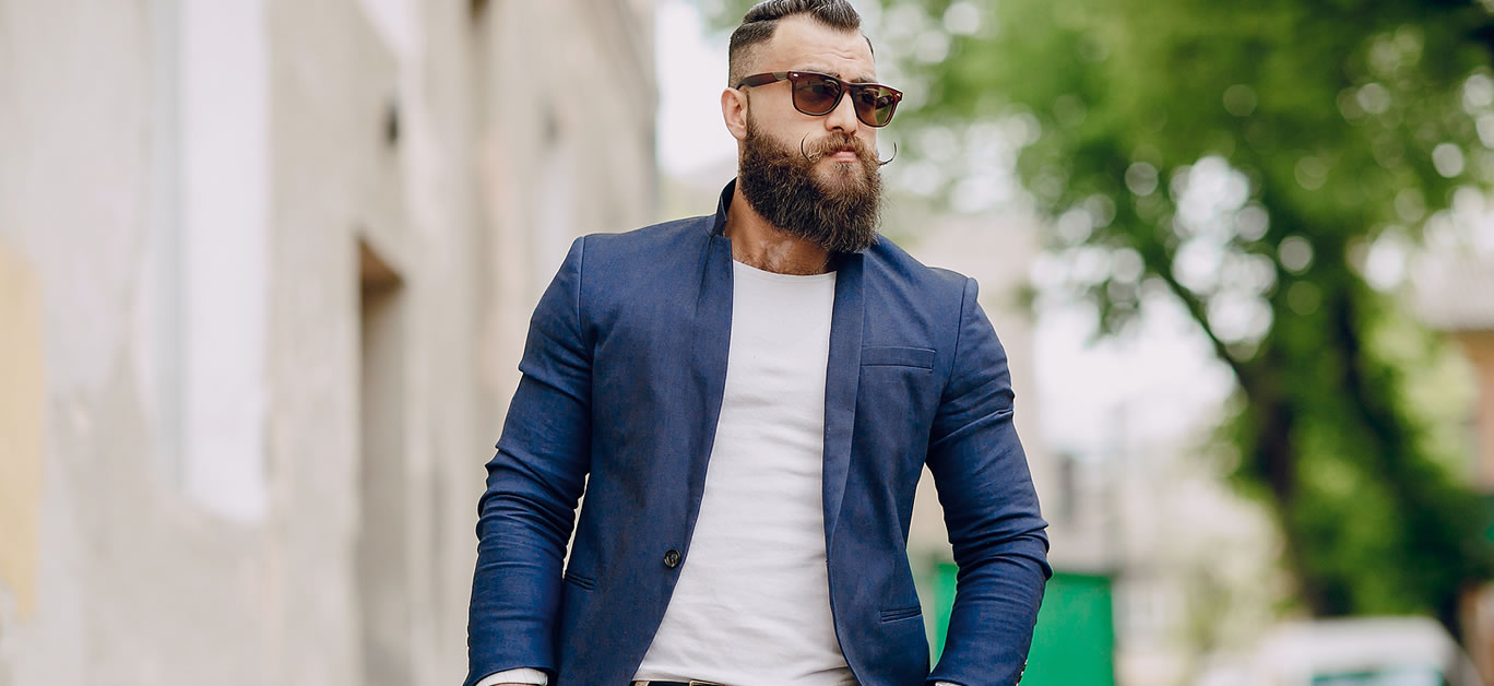 manly bearded man dressed stylishly stands on street