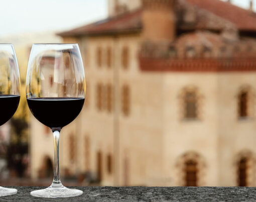 Two glasses of Barolo wine on a windowsill with the castle of Barolo (Piedmont, Italy) blurred on the background