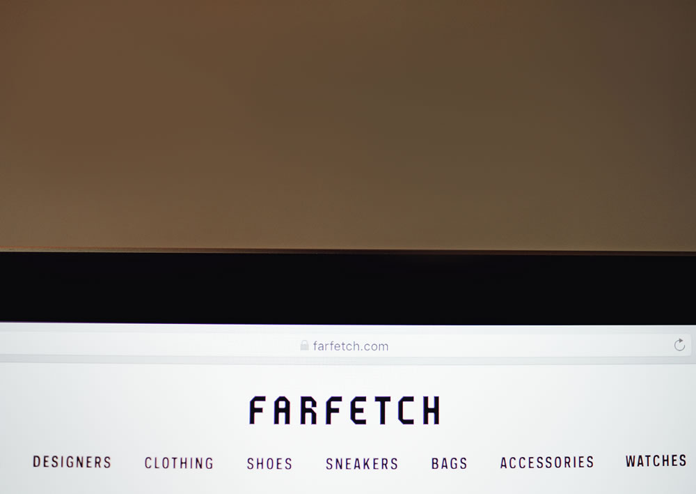 Farfetch online fashion store. Laptop with screen of farfetch site.