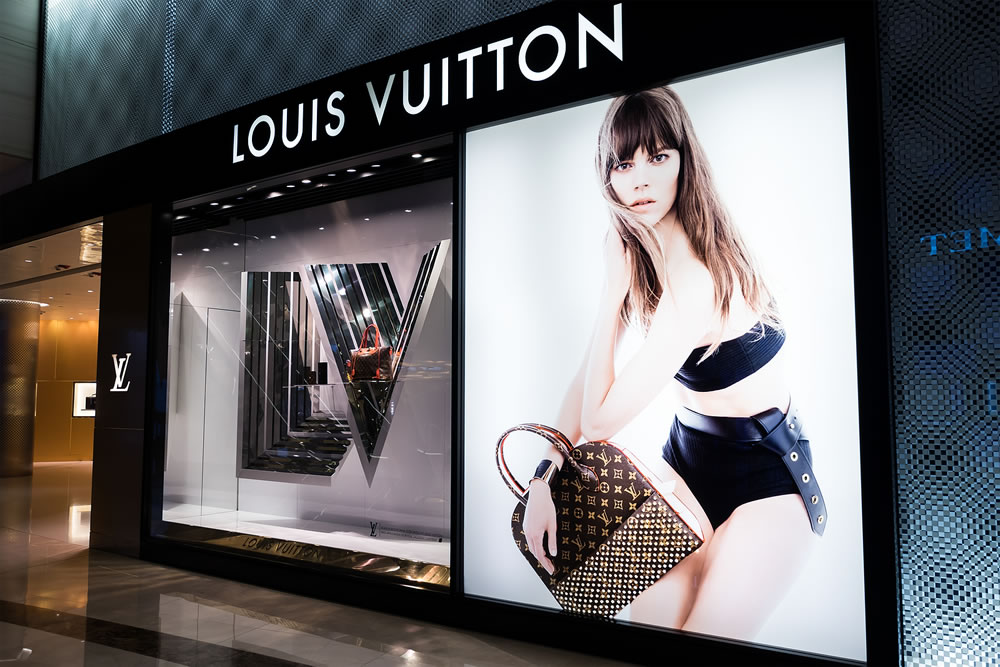 Louis Vuitton boutique display window with mannequin in luxury clothes and accessories for exclusive shopping