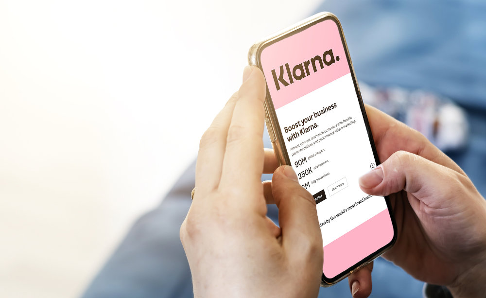 Female hands holding a phone with Klarna company web page on screen