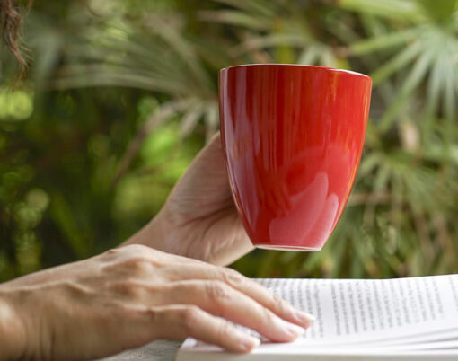 Woman having a cup of coffee and reading a book, close up