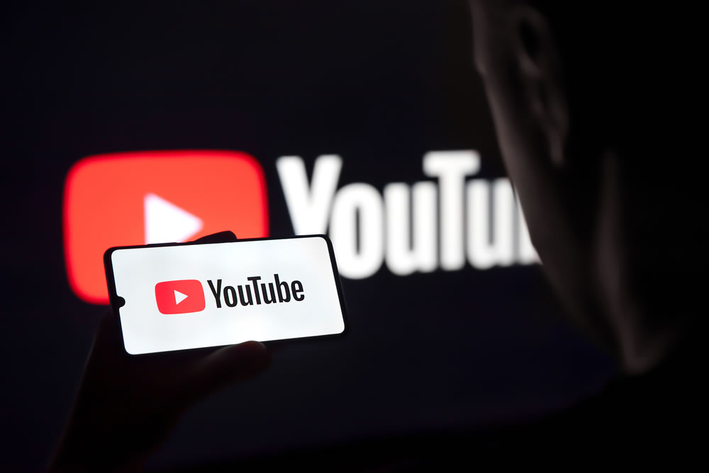 Man holding smart phone with YouTube logo on screen