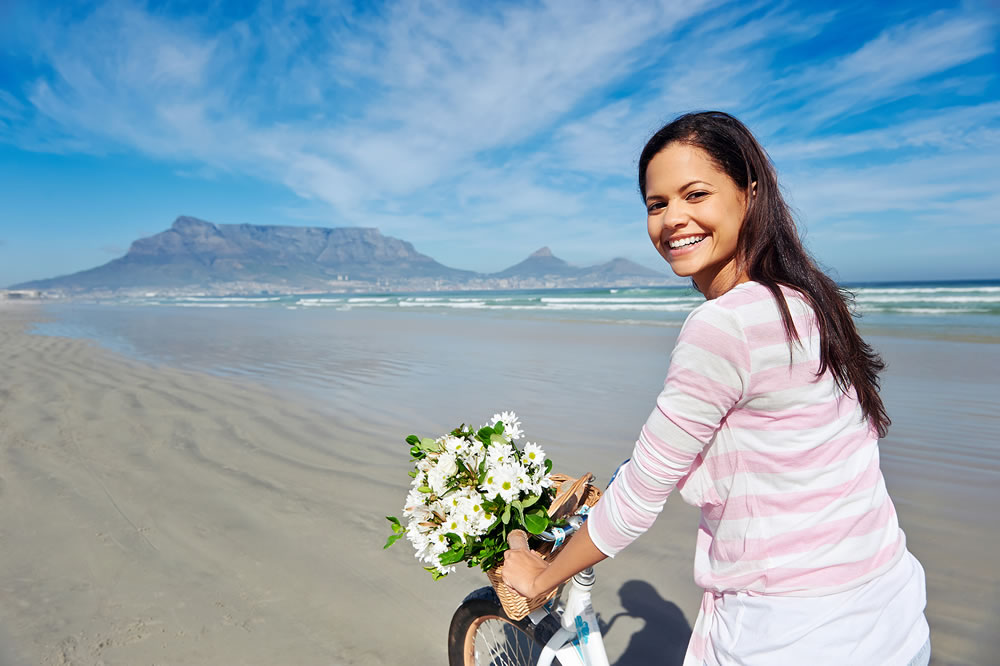 Woman with bicycle on beach in Cape Town, South Africa and Table Mountain