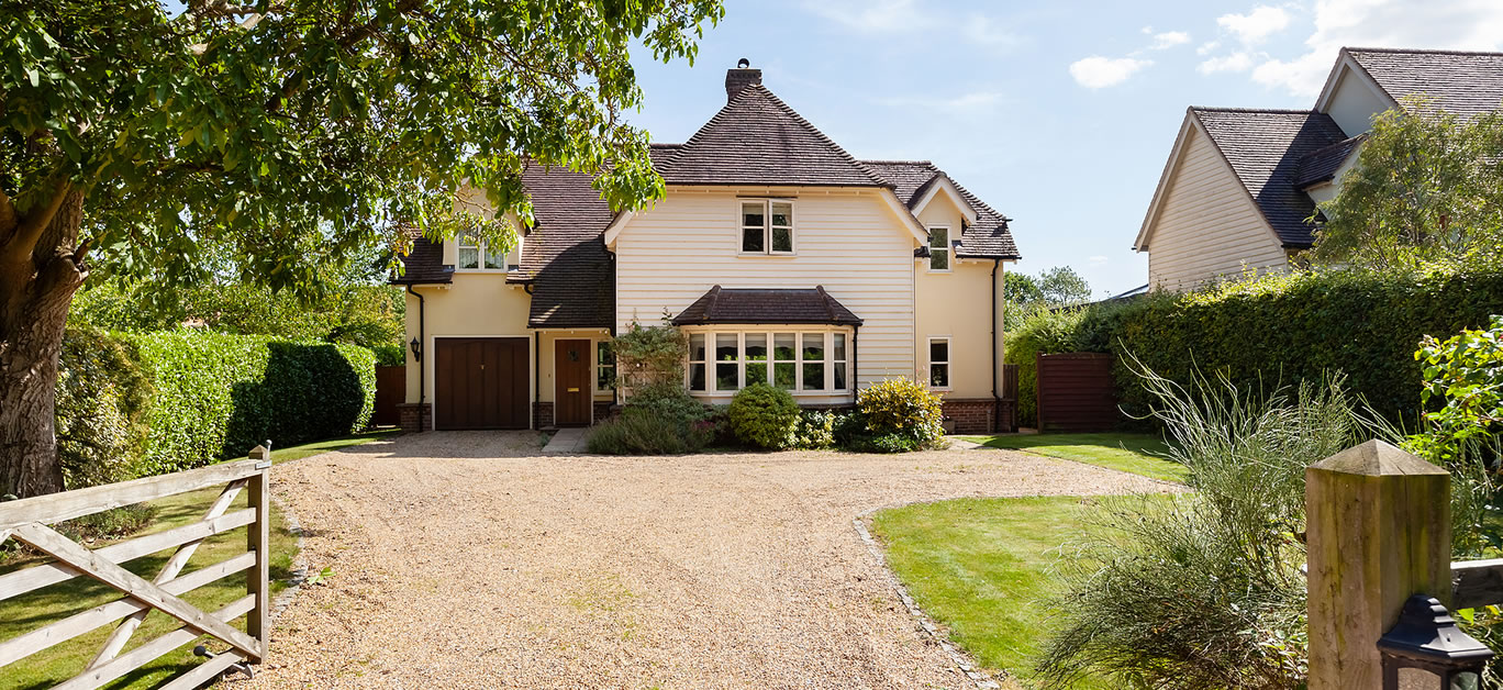 Traditional appearing modern british home with wooden cladding, bay window and set back from the road with a gravelled driveway