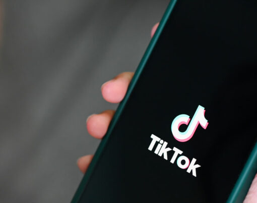 Child holding smartphone with TikTok application icon on Apple iPhone 13 Pro