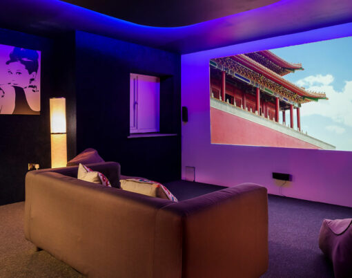 Modern home movie / cinema room with sofa, chairs and dimmed lighting