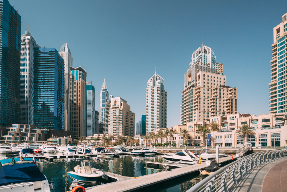 Yachts are moored at city pier, jetty in Dubai Marina. Cityscape skyline.