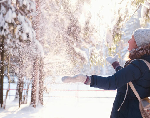 Happy young woman play with snow in sunny winter day